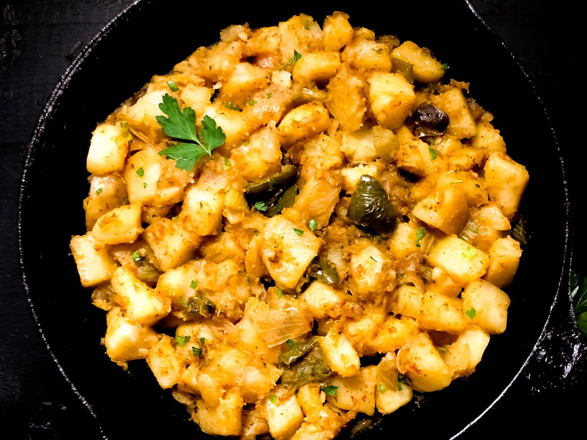 Cajun smothered potatoes in a cast iron skillet.