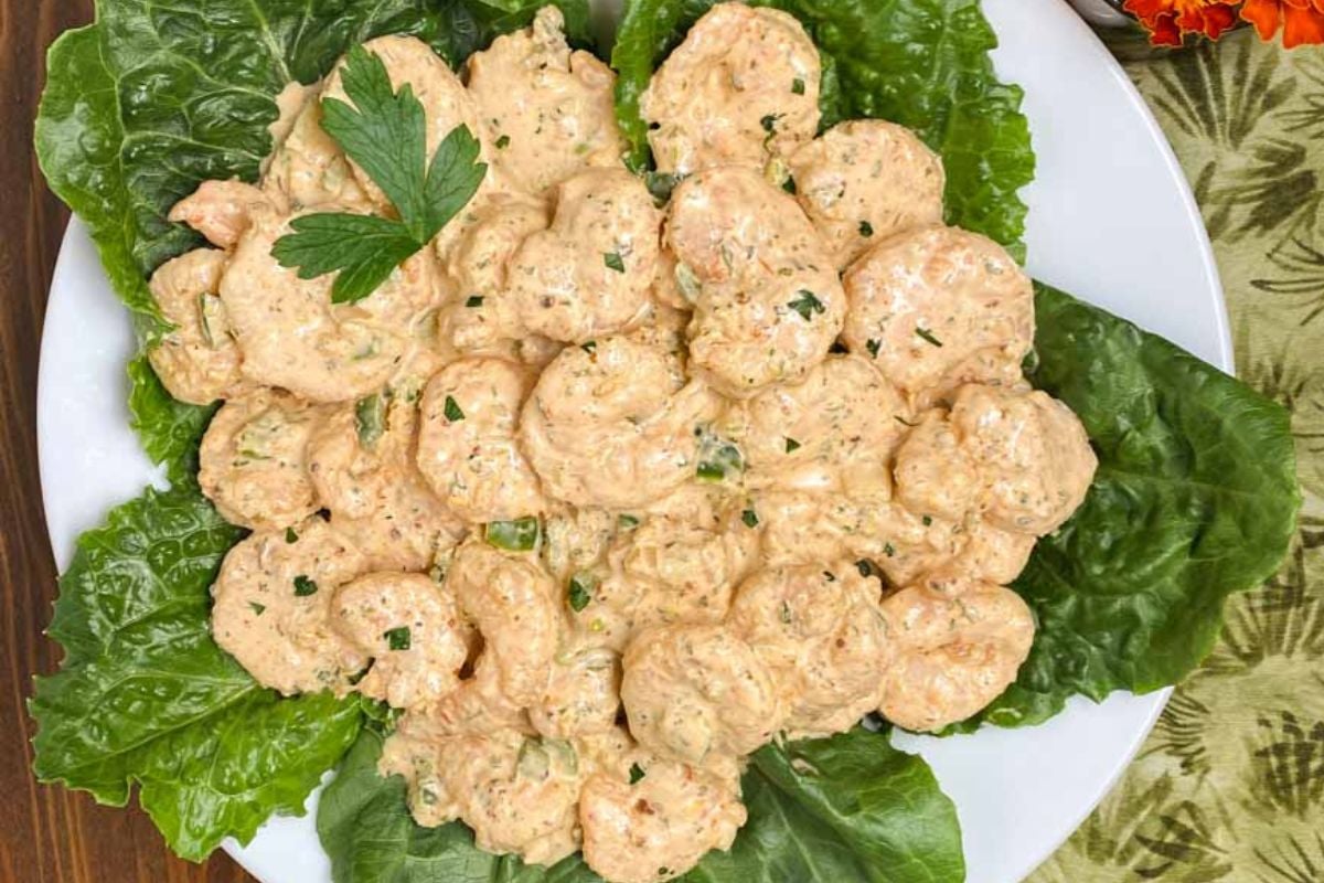 Shrimp remoulade over baby spinach leaves on a white plate. 