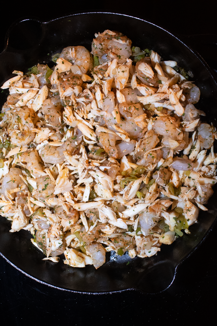 Shrimp, crab meat, and chopped vegetables in a skillet.