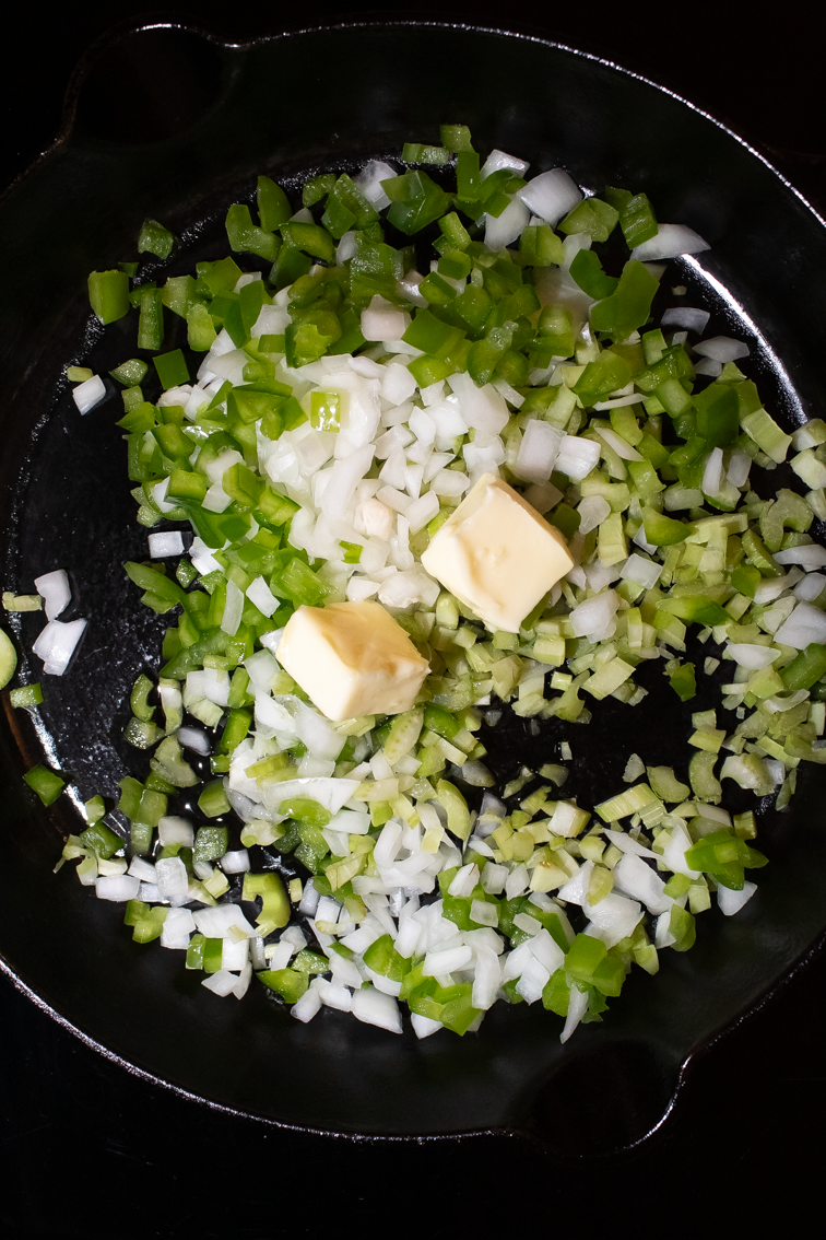 Chopped Cajun trinity veggies in a black cast iron skillet.