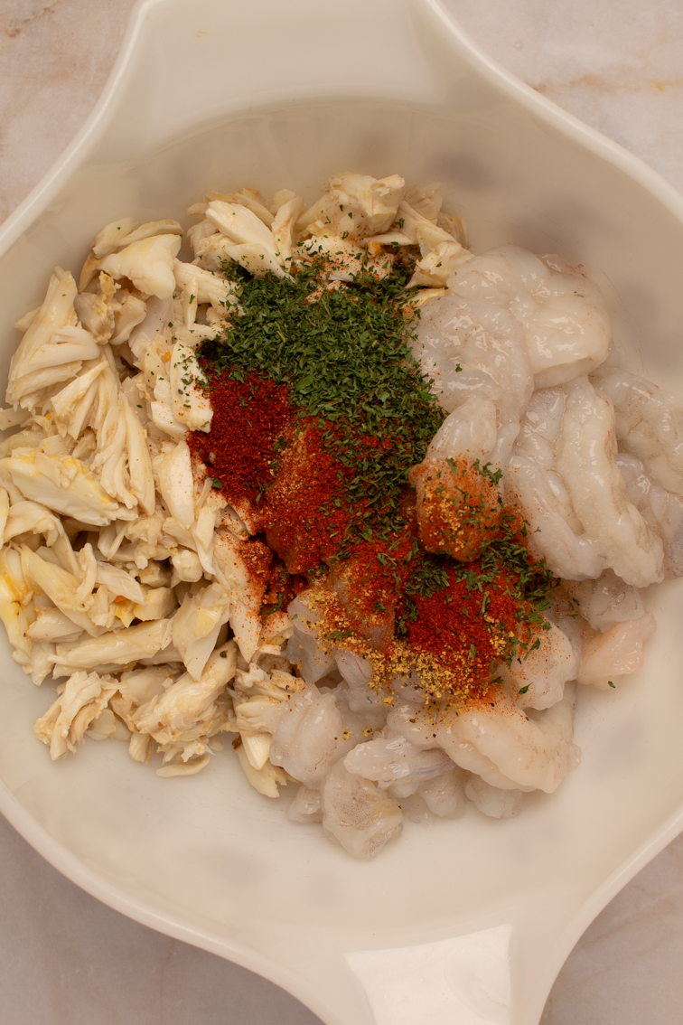 Dried seasonings over seafood in a white bowl.