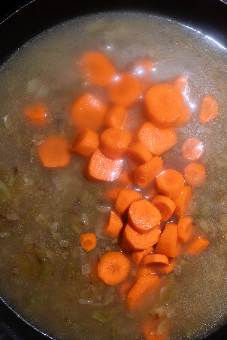 Carrots on top of a roux in a skillet.
