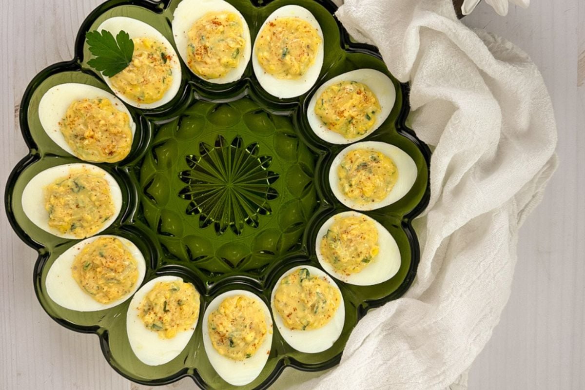 Cajun deviled eggs in a green glass serving dish.;