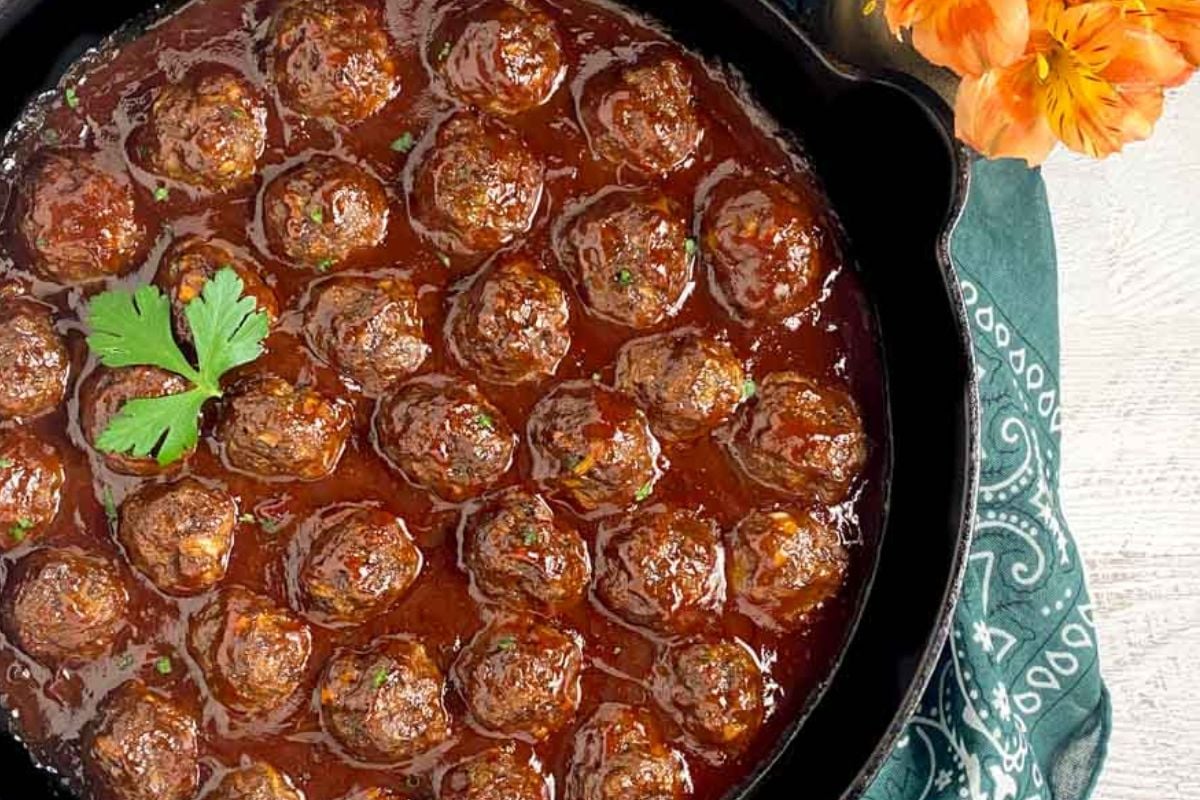 Cocktail meatballs in a large black cast iron skillet.
