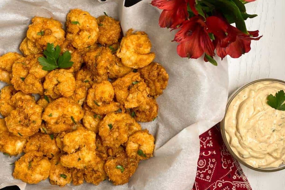 Cajun fried shrimp on parchment paper in a cast iron skillet.