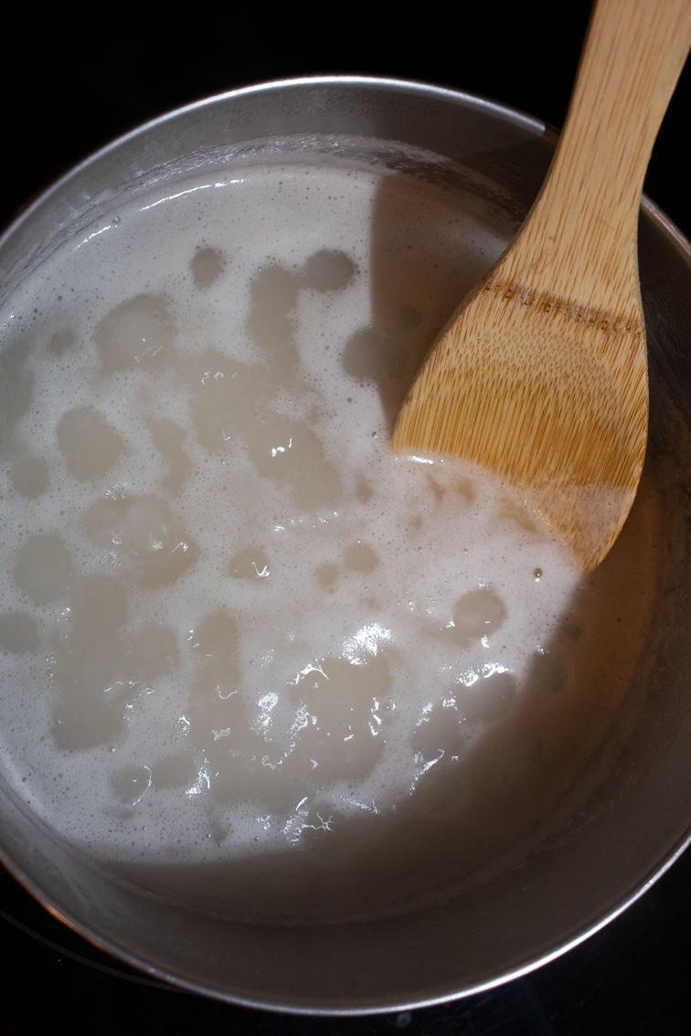 Rice, water, and salt boiling in a small pot on the stove.