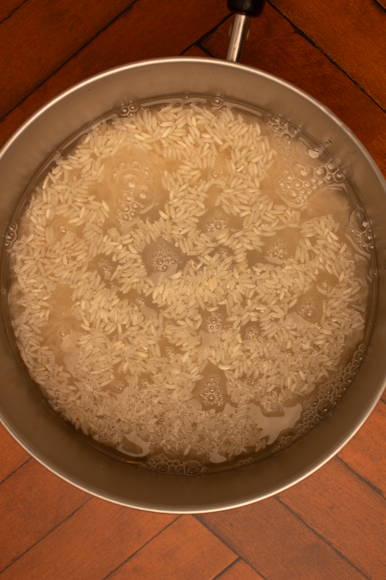 Rice, water, and salt in a small pot on the stove.