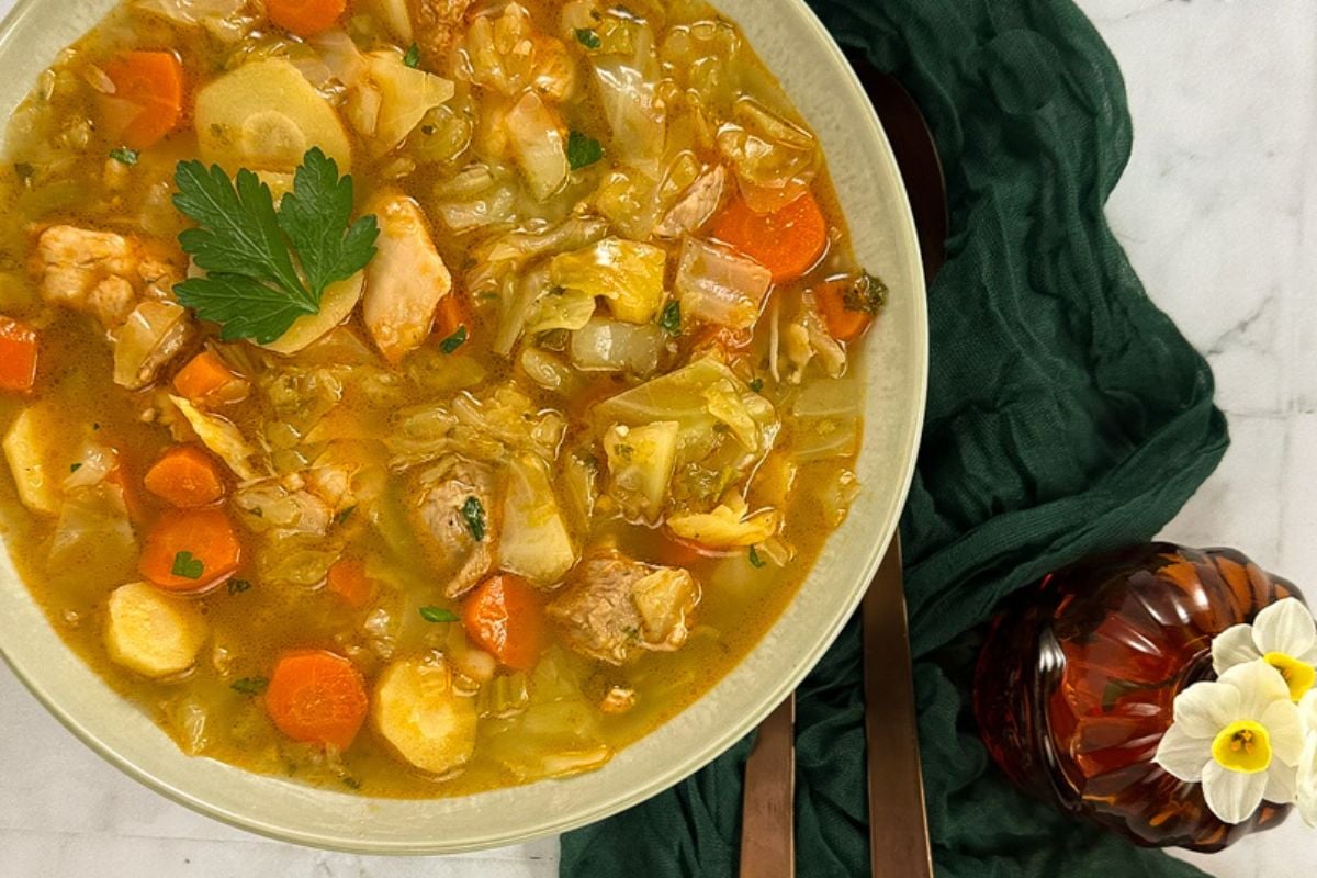 Cajun-style chicken and cabbage soup with carrots and parsnips in a bowl. 
