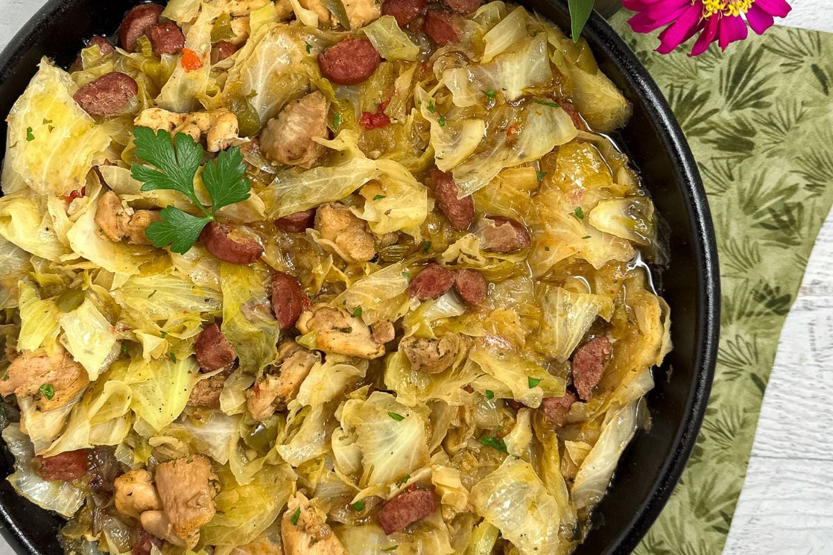 Cajun smothered cabbage with chicken and sausage in a cast iron skillet.