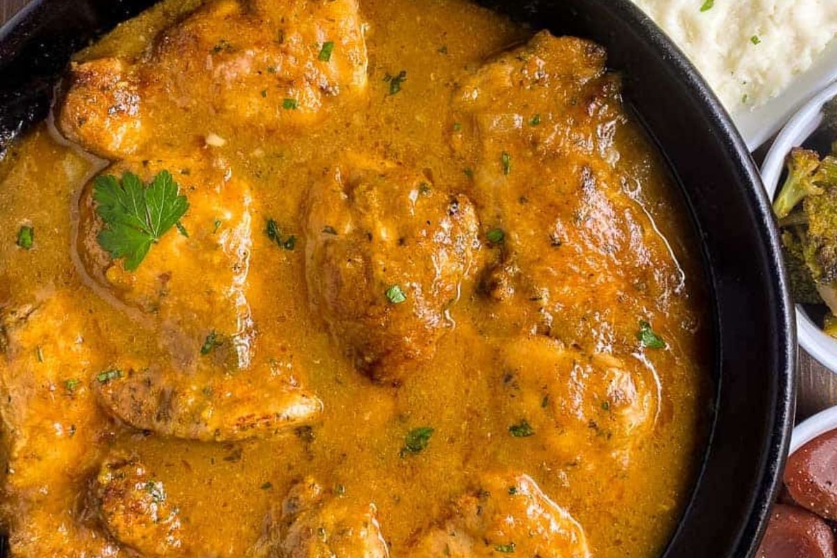 Cajun smothered chicken in a black cast iron skillet.