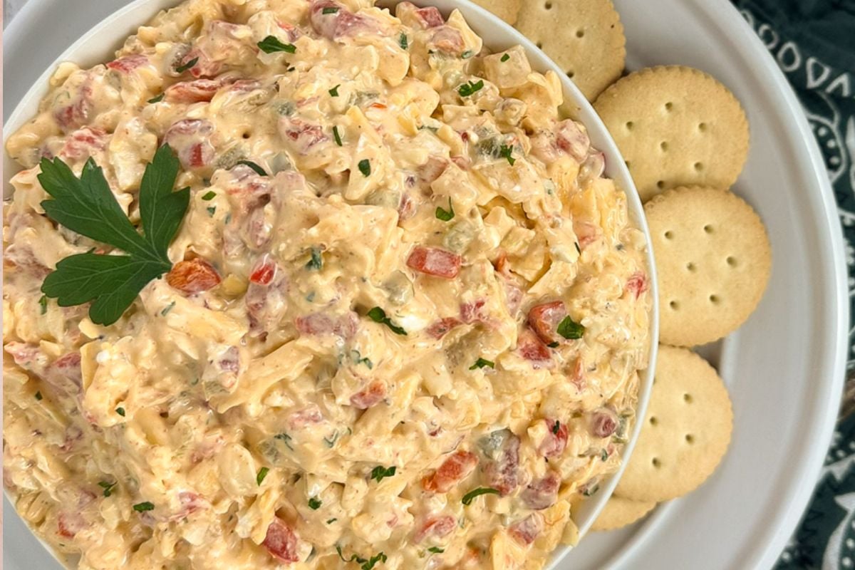 Cajun pimento cheese in a round white bowl with round crackers.