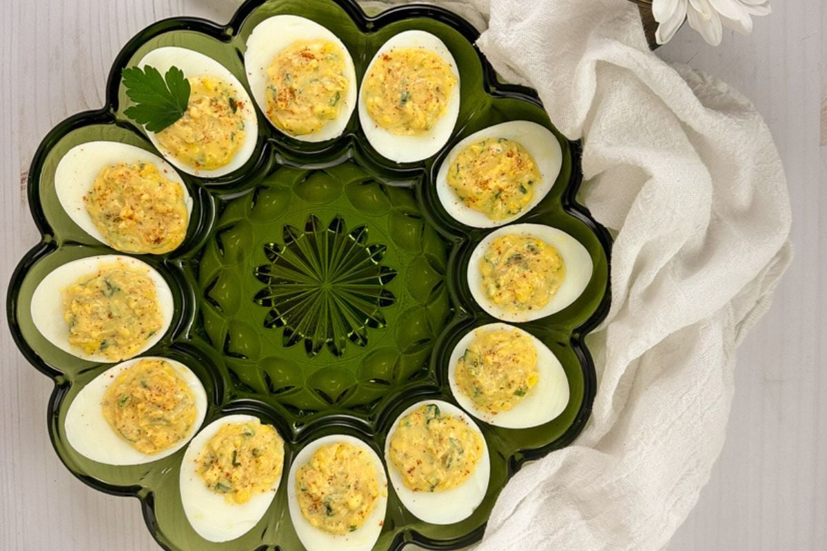 Cajun deviled eggs in a vintage green glass serving tray.