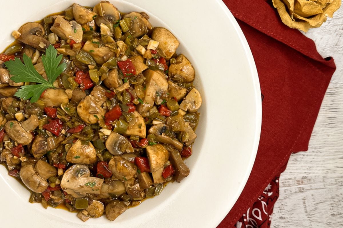 Cajun mushrooms in a white bowl alongside a red bandana napkin.