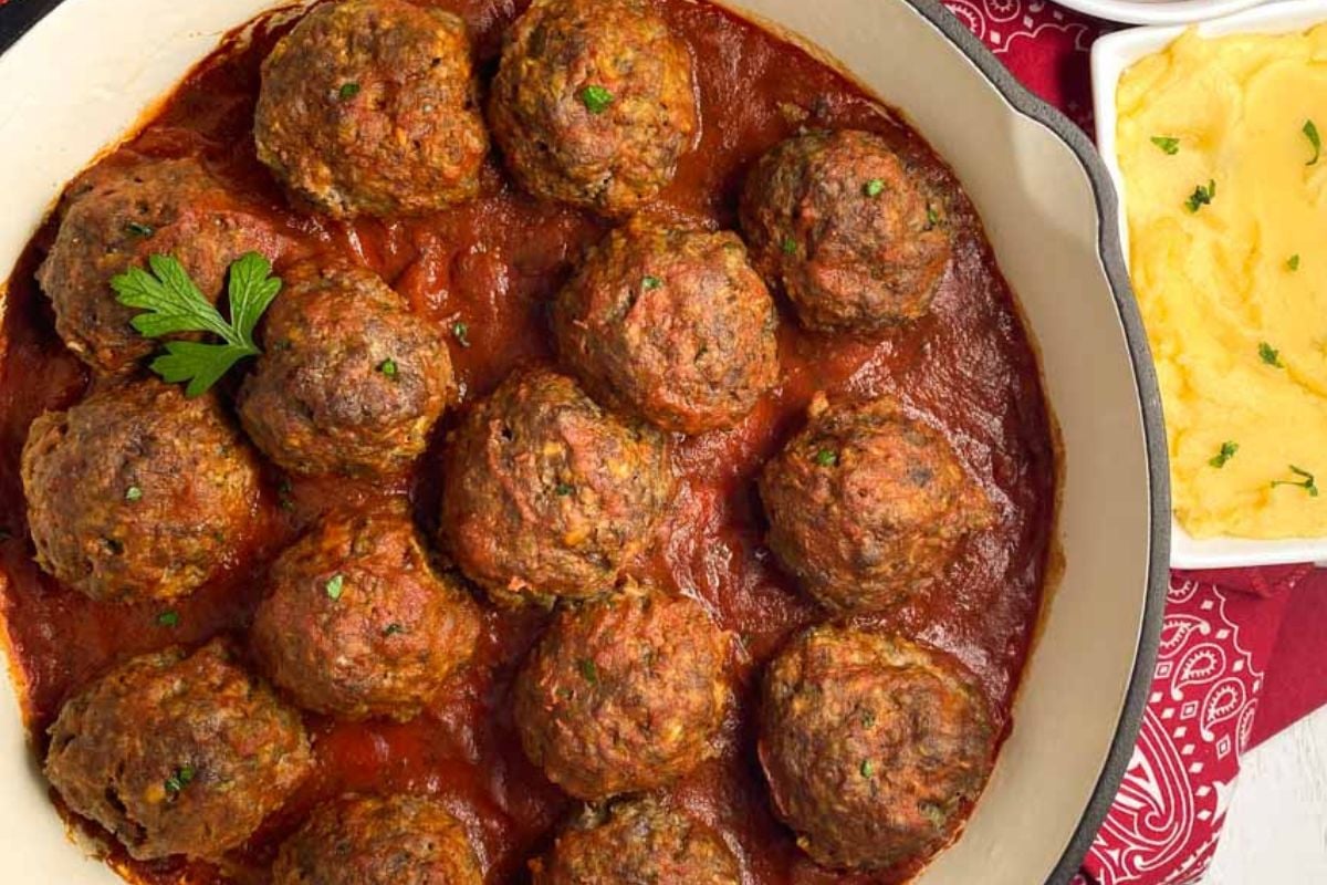 Creole meatballs in tomato sauce in a red enameled skillet.