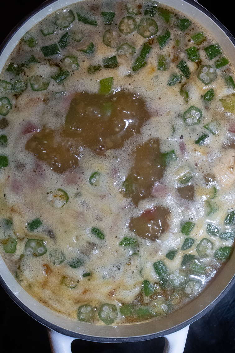 Chicken and sausage gumbo boiling in a large oval cast iron Dutch oven.