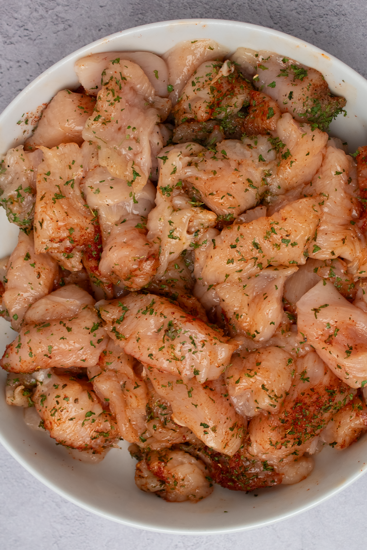 Seasoned chicken cubes in a large white mixing bowl.