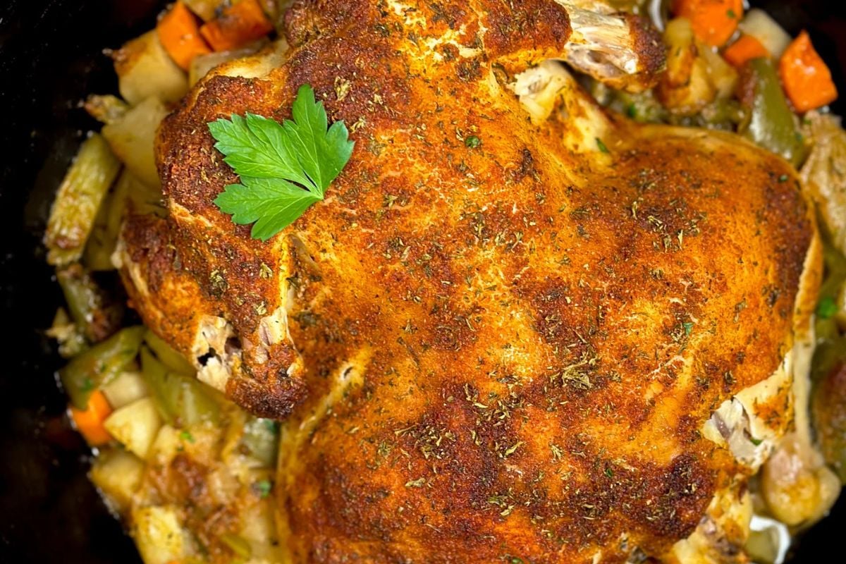 Cajun roasted chicken over vegetables in a large cast iron Dutch oven. 