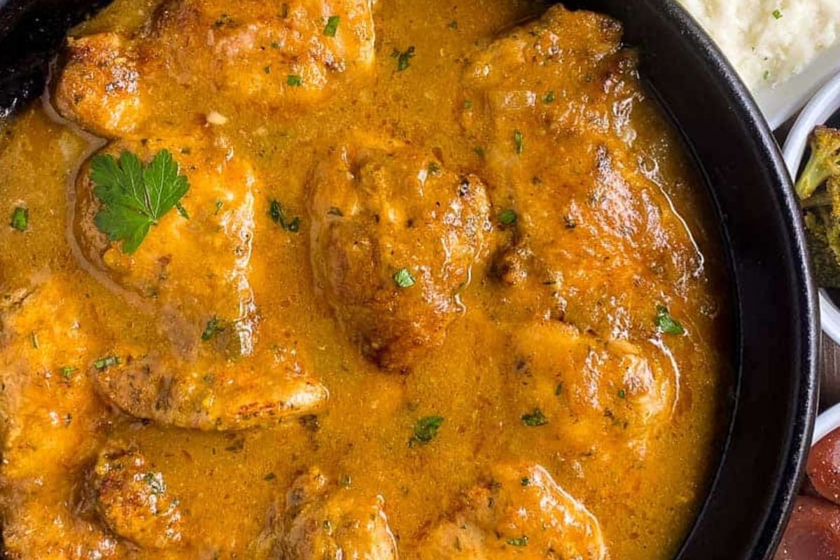 Cajun smothered chicken in a black cast iron skillet.