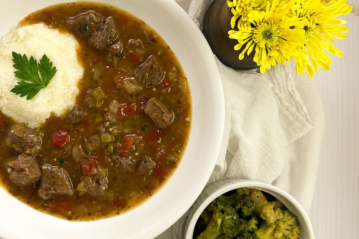 Grillades and grits in a round white bowl.