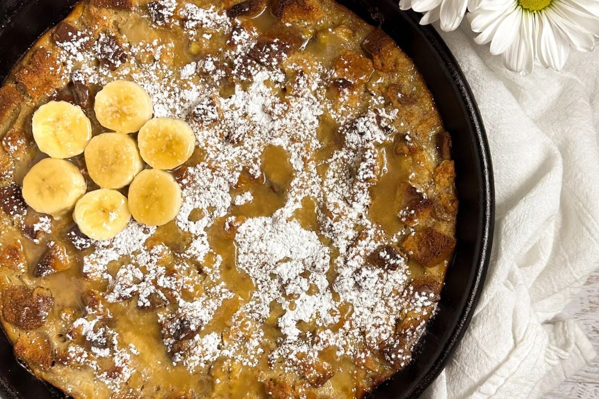 Bananas Foster bread pudding in a large black cast iron skillet.