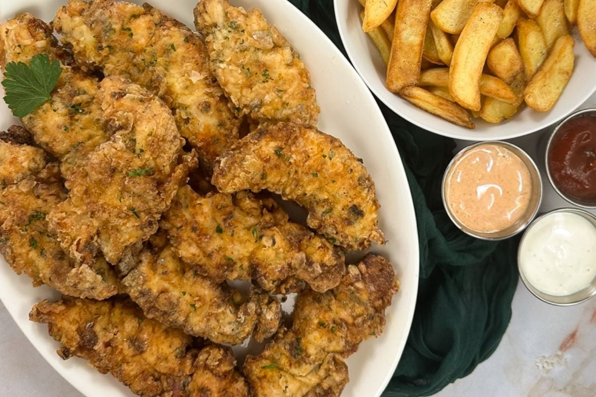 Cajun fried chicken tenders with fries and three sauces.