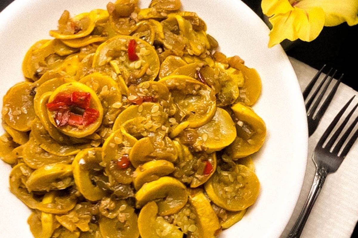Cajun smothered squash in a round white bowl.