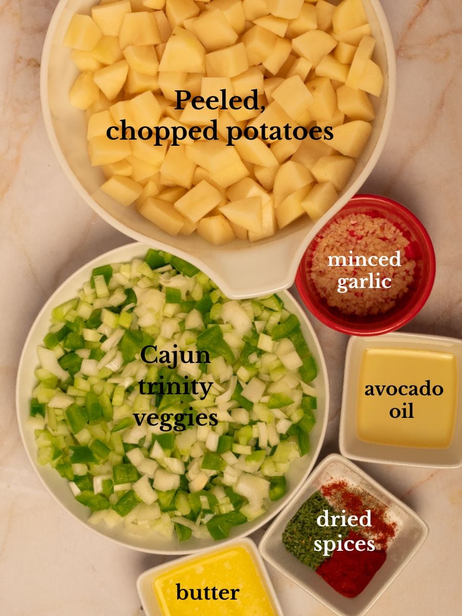 Labeled ingredients for Cajun roasted potatoes in bowls on a white marbled background.