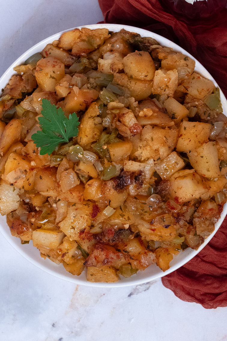 Cajun roasted potatoes in a round white bowl alongside a red napkin.