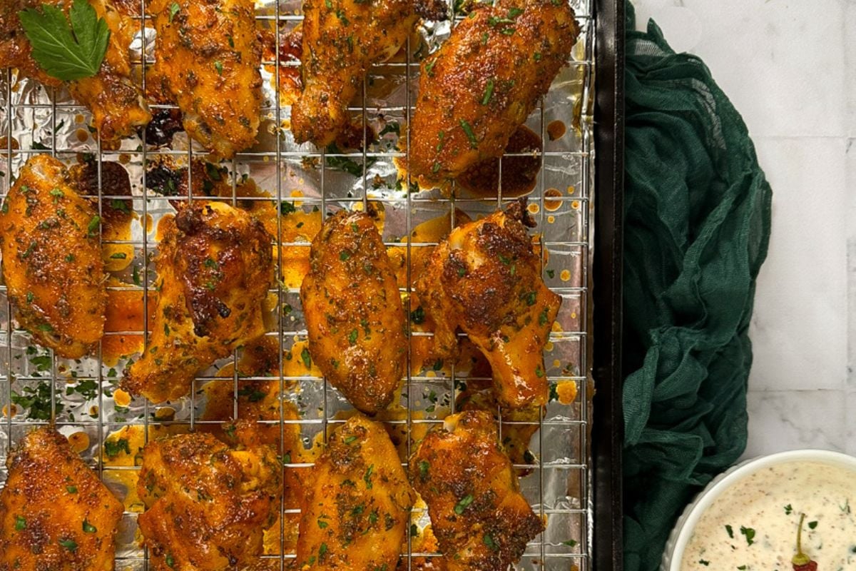Cajun baked chicken wings on a rack over a cast iron pan.