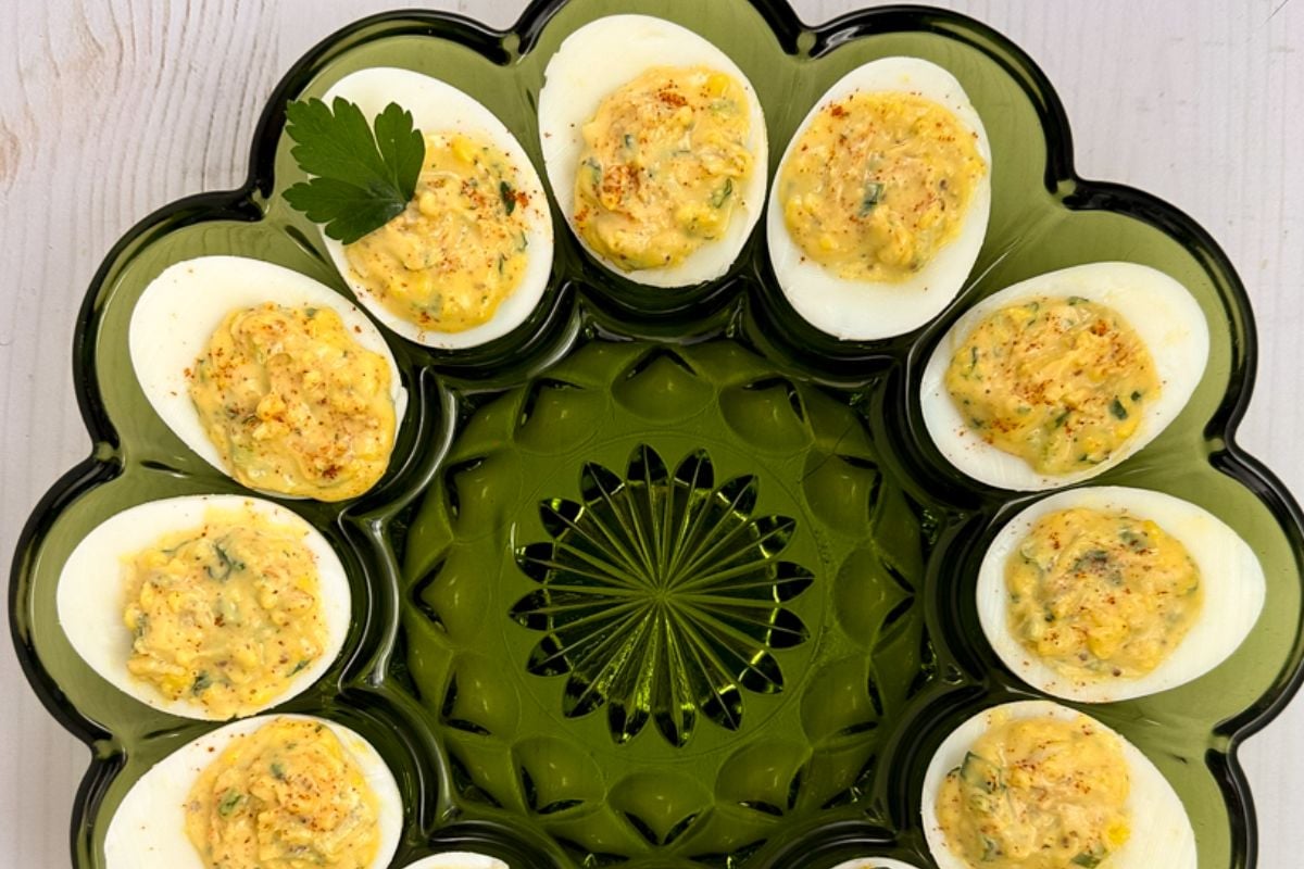 Cajun deviled eggs in a green glass dish.