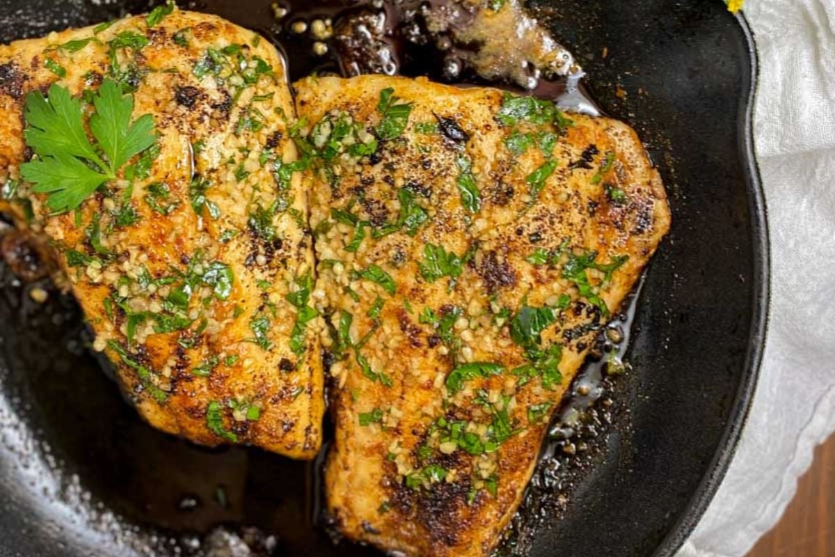 Pan-seared snapper in a green cast iron pan.
