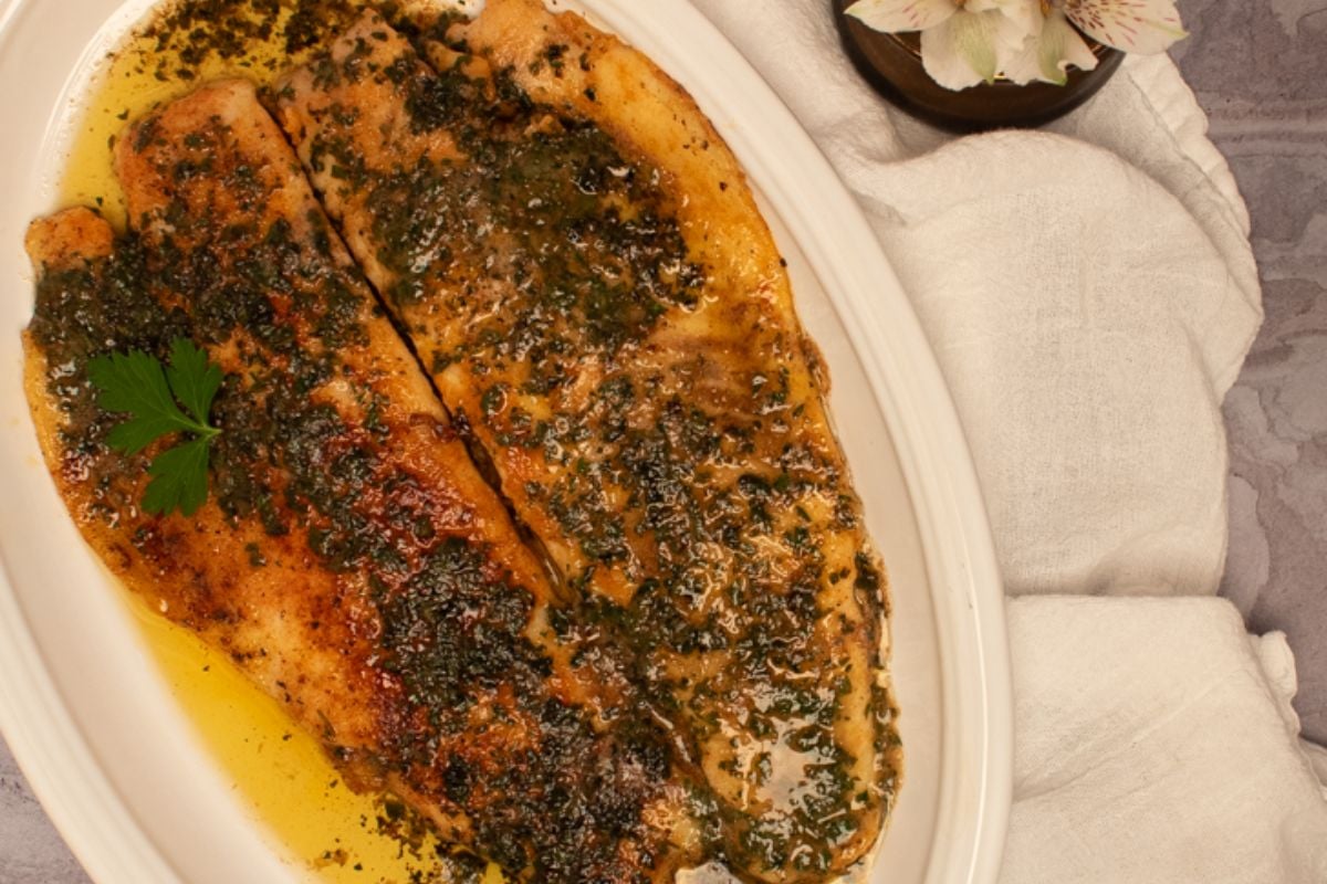 Two trout meuniere fillets on an oval white serving platter.