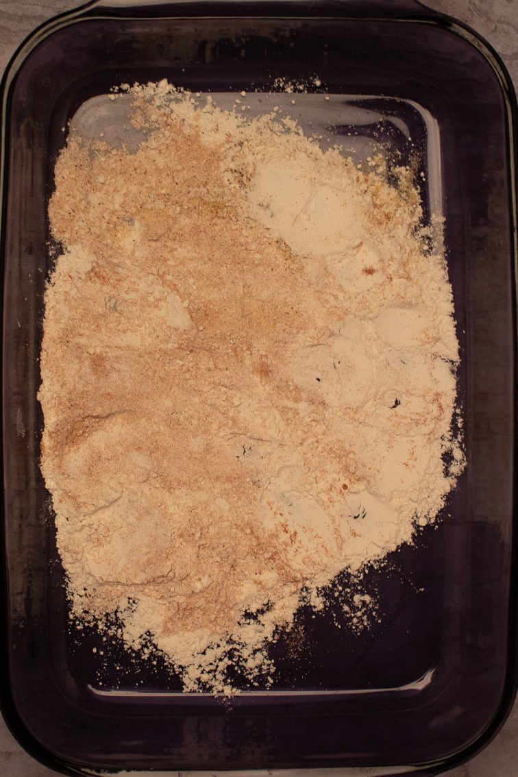Seasoned flour for trout meunière in a purple 9 x 13 baking dish.