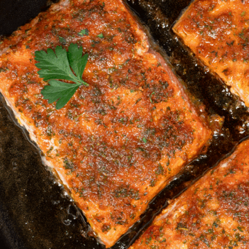 Closeup of one Cajun baked salmon fillet in a cast iron pan.