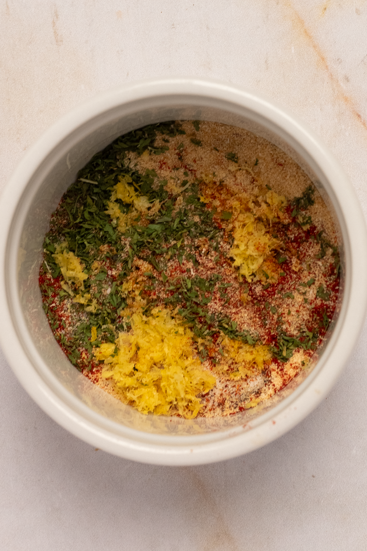 Dried Cajun seasonings and lemon zest in a small white bowl.