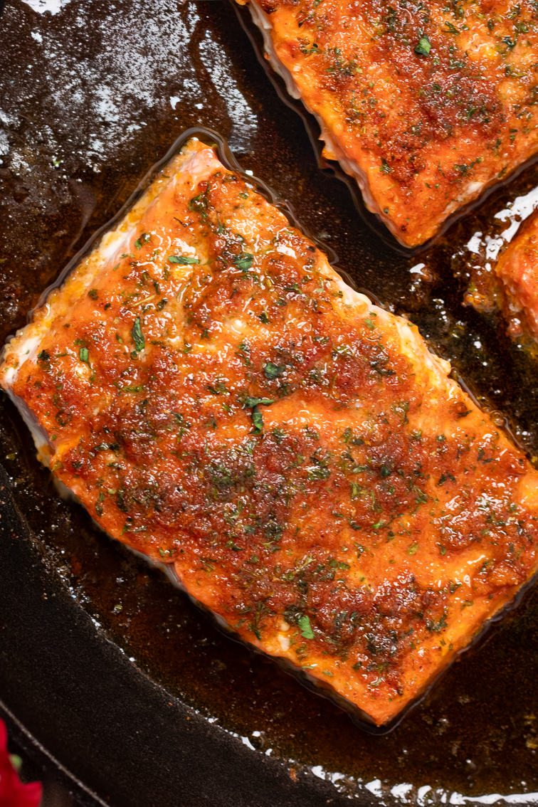 Another closeup image of one Cajun baked salmon fillet in a pan.