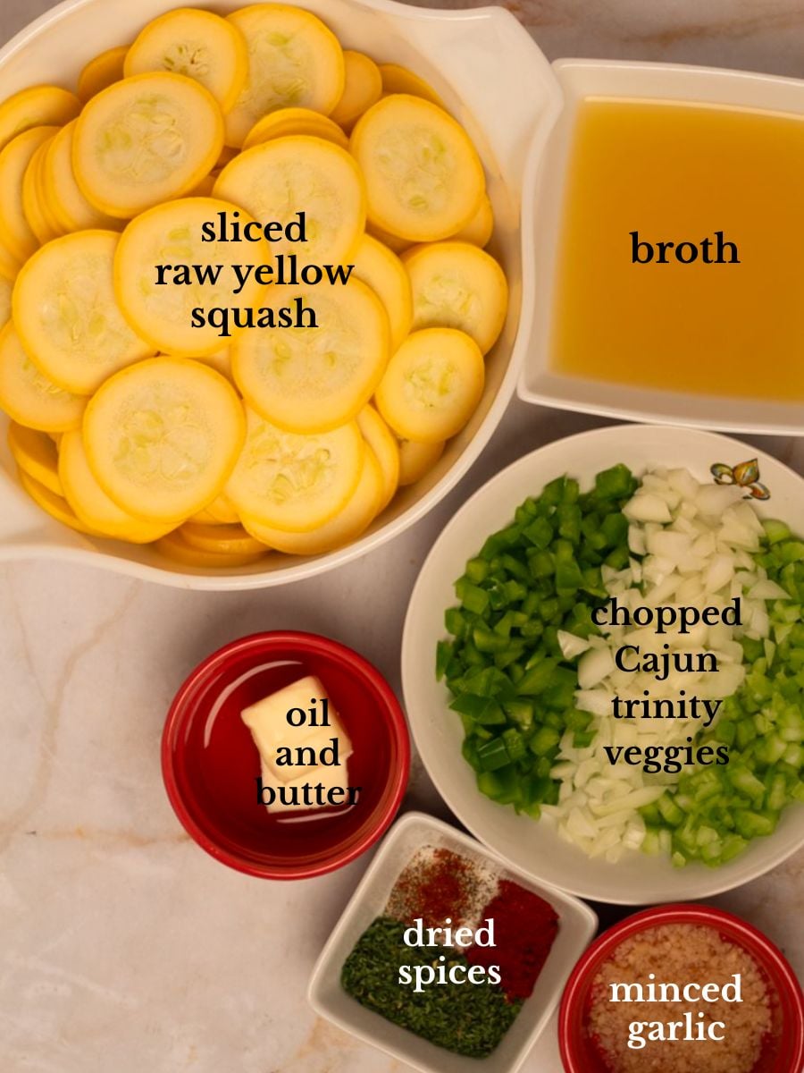 Ingredients for Cajun smothered yellow squash in bowls on a white marbled background. 