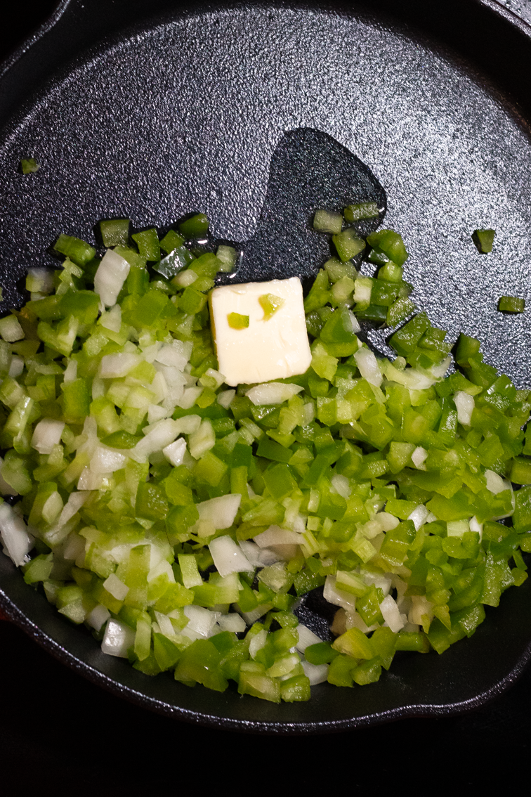 Cajun trinity veggies with butter and oil in a pan for the start of the Cajun smothered yellow squash recipe.