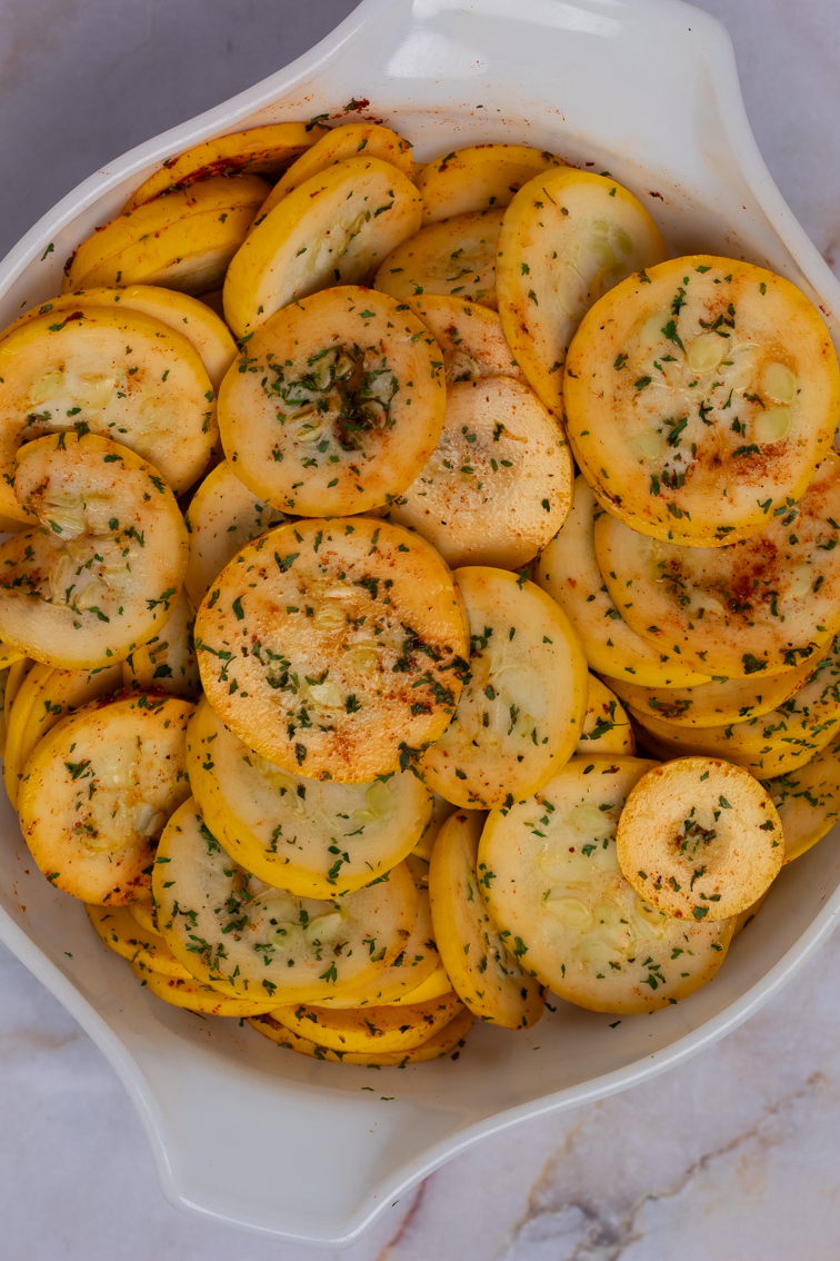 Cajun seasoned yellow squash in a big white bowl.