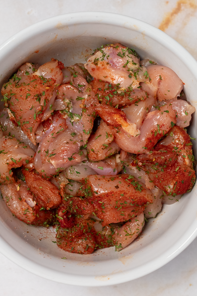 Seasoned chopped chicken thighs in a bowl.