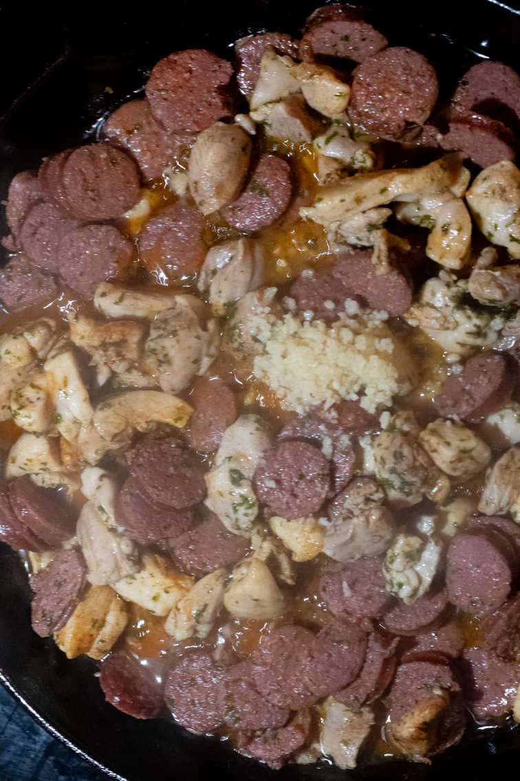 Browed sausage and chicken with minced garlic in a pan.