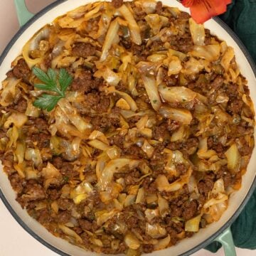 Ground beef and cabbage in a light green skillet.