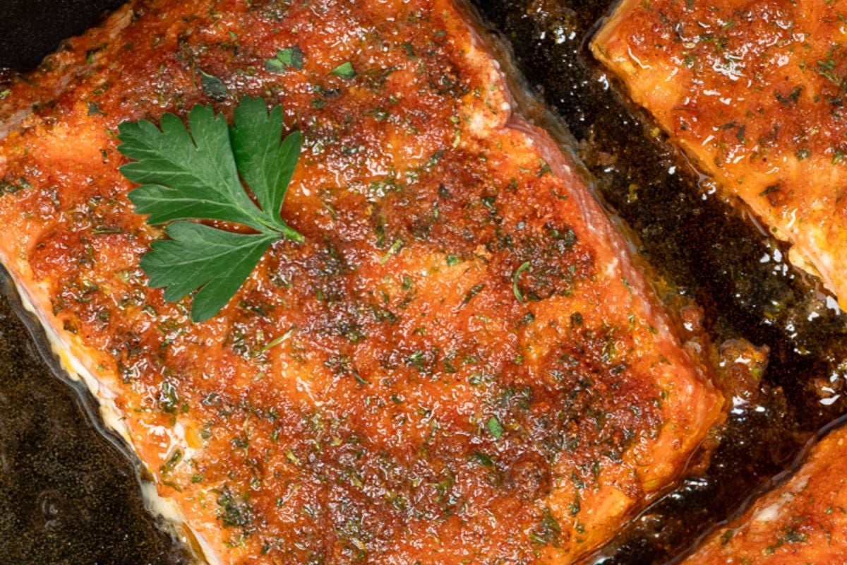 Closeup of one Cajun honey butter salmon fillet in a pan.