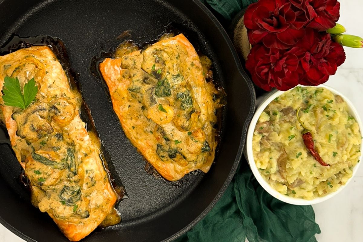 Shrimp and spinach stuffed salmon in an enameled cast iron skillet.