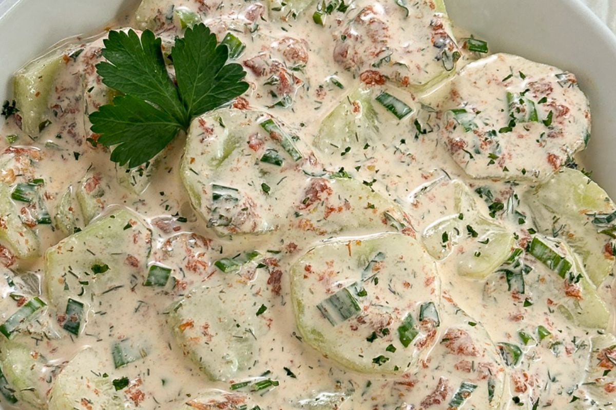 Creamy cucumber salad with a whole parsley leaf garnish in the top left corner.