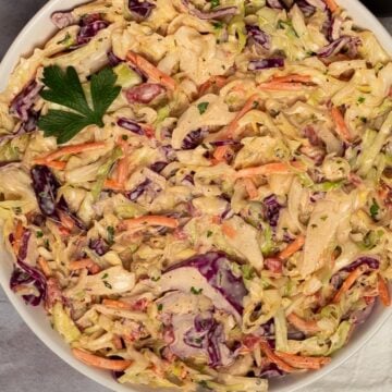 Square closeup image of Cajun coleslaw with a parsley leaf garnish.