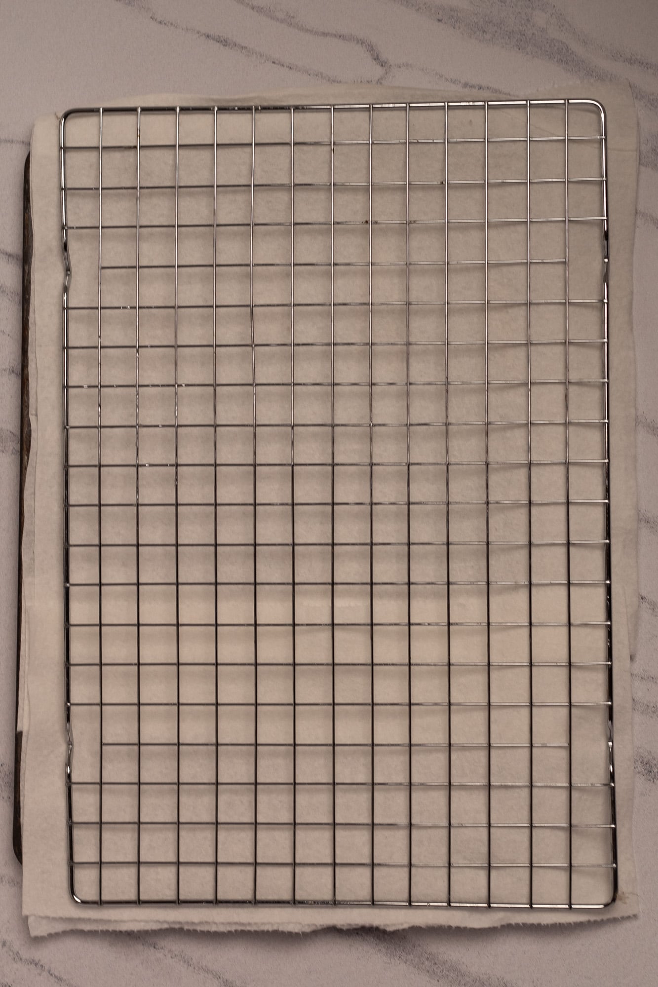 A metal wire rack situated over a paper towel-lined aluminum baking tray.