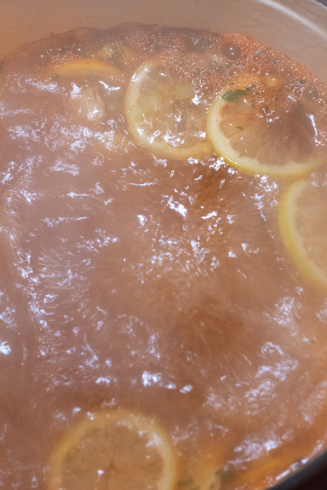 Boiling liquid for poached shrimp in a pot on the stove.