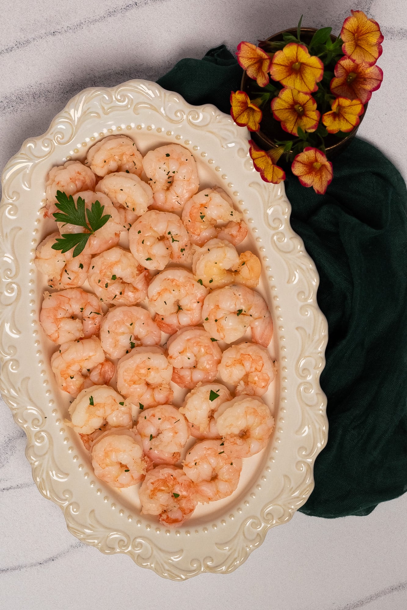 Poached shrimp on an oval antique white serving platter.