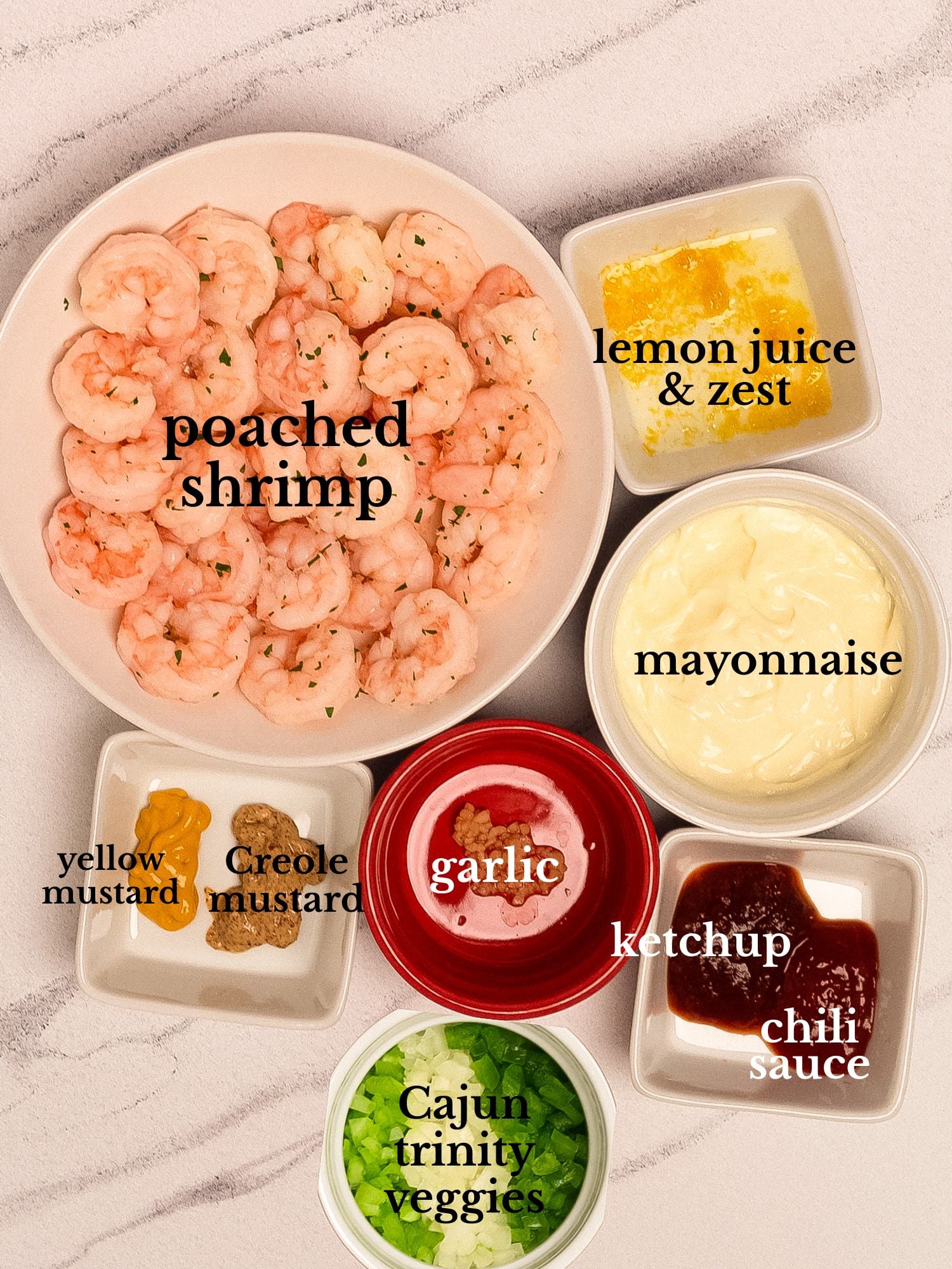 Ingredients for shrimp remoulade in bowls on a white background with grey marbling.